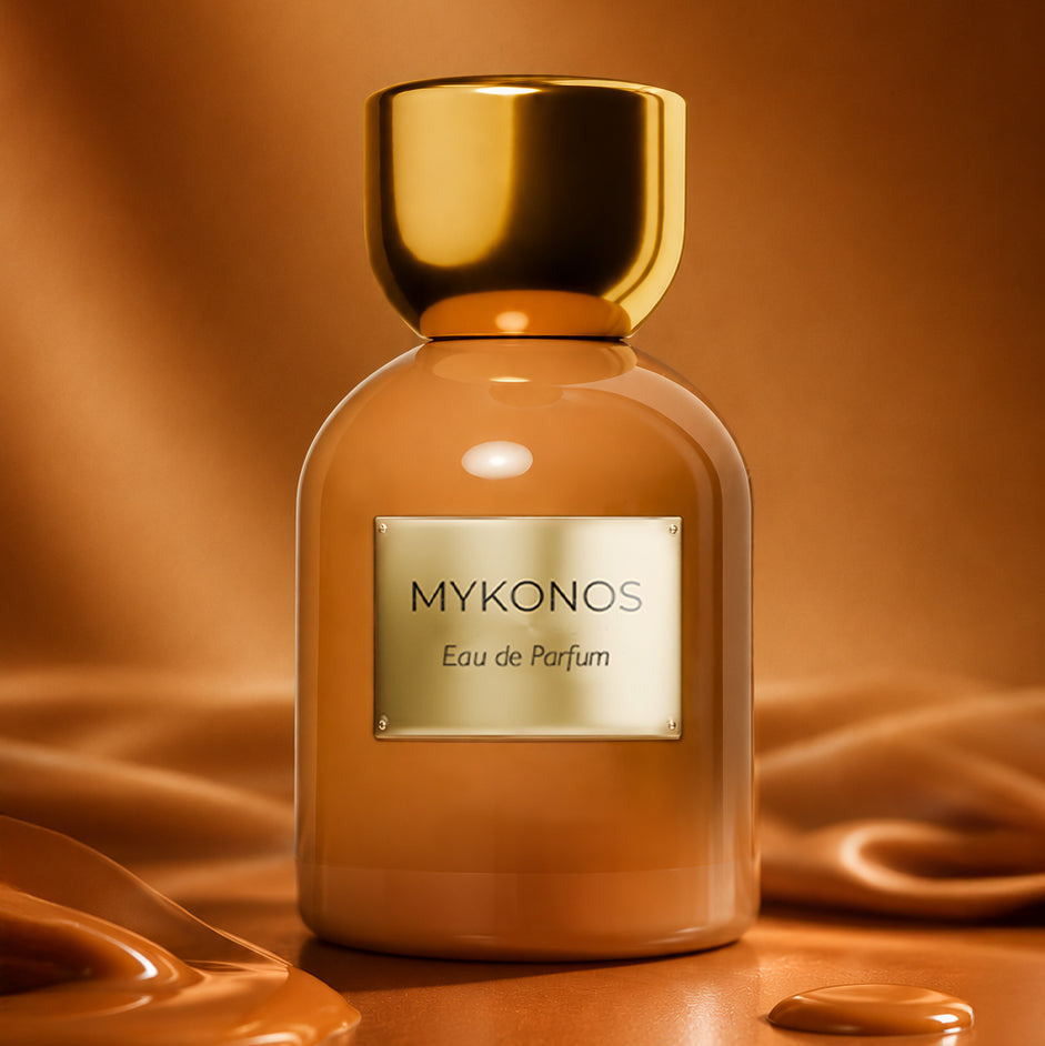 A bottle of MYKONOS Eau de Parfum with a glossy amber-brown body and a metallic gold cap, set against a draped, warm brown background with liquid-like textures.