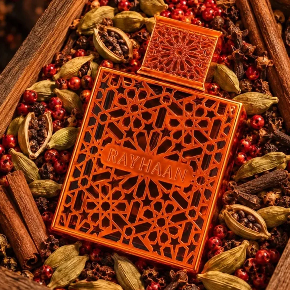 Rayhaan Vantage 100ml perfume bottle with intricate orange geometric lattice casing, surrounded by aromatic spices.